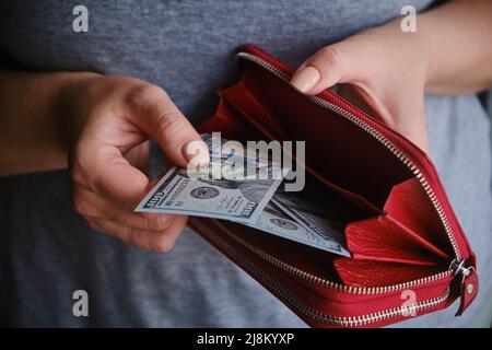 Gros plan sur les mains de femmes d'une femme qui prend de l'argent de son sac à main rouge, compte l'argent des billets en dollars Banque D'Images