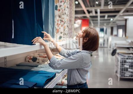 Une femme asiatique choisit le tissu et le textile au centre commercial. Banque D'Images