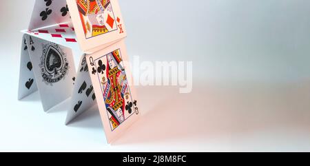 Maison de cartes à jouer empilées sur un fond blanc avec de la place pour le placement du texte Banque D'Images