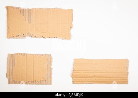 Trois morceaux de carton ondulé brun sur fond blanc. Cartes de notes en carton kraft vierge et déchiré avec espace de copie pour le texte. Vue de dessus Banque D'Images
