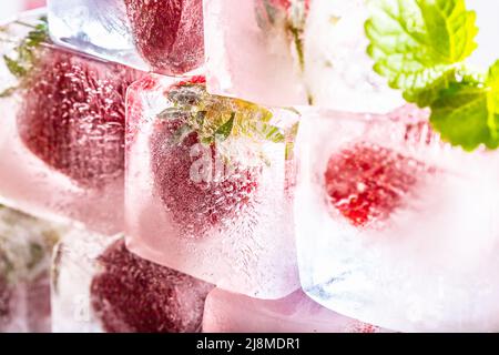 Fraises fraîches congelées dans des glaçons avec des feuilles de melissa. Banque D'Images