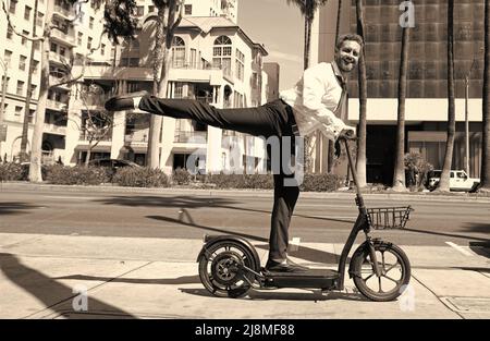 homme d'affaires heureux à cheval électro-scooter sur fond de paysage urbain, transport de location. Banque D'Images