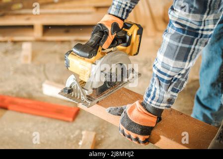 Entrepreneur en construction découpe à la taille de la poutre en bois à l'aide d'une scie circulaire portative photo de près. Thème équipement industriel. Banque D'Images