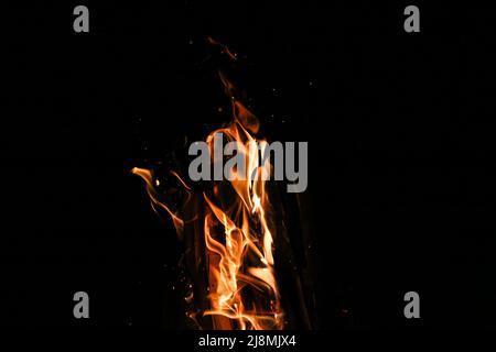 Flammes d'un feu de camp avec de nombreuses étincelles sur fond noir Banque D'Images