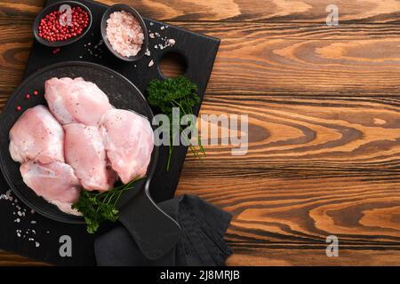 Filet de cuisse de poulet cru sans peau avec des herbes et des épices sur fond de bois ancien. Viande de volaille agricole. Vue de dessus avec espace de copie. Maquette. Banque D'Images