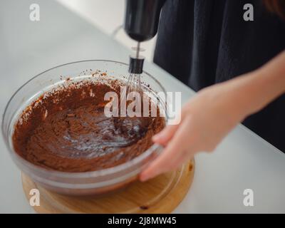 femme mélanger la poudre de cacao, le sucre et la farine pour faire de la pâte avec du chocolat fondu et des noix pour un délicieux gâteau au brownie maison. gâteau fait maison par maison Banque D'Images