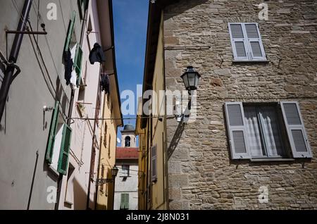 Mur en pierre de la vieille maison avec fenêtres avec volets bleus, rideaux dessinés et lanterne vintage sur la façade du bâtiment dans la ville italienne Borgo Val di Taro Banque D'Images