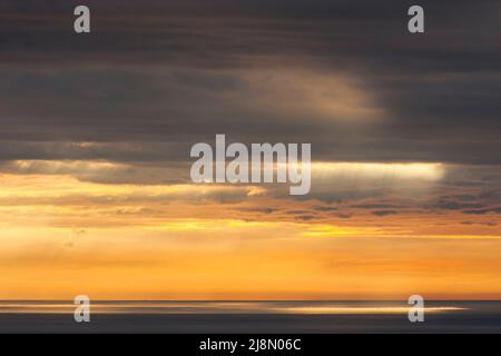 Lever de soleil d'été avec lumière dorée qui traverse les nuages nimbostratus au-dessus de la mer d'Irlande. Dublin, Irlande Banque D'Images