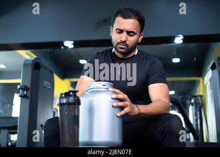 bodybuilder boire ou prendre de la poudre de protéine et mélanger avec de l'eau sur la bouteille en secouant à la salle de gym - concpet de gain musculaire, entraînement de forme physique et Banque D'Images