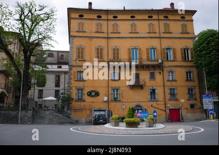 Borgo Val di Taro, Italie - Mai 2022 : ancien bâtiment jaune de plusieurs étages de style italien typique avec des volets en bois sur les fenêtres au rond-point Banque D'Images