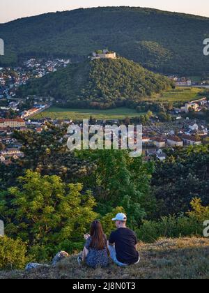 Couple assis sur un point de vue à flanc de colline surplombant Hainburg an der Donau et les ruines du château en Autriche Banque D'Images