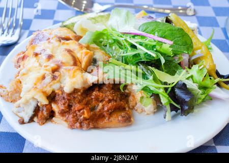 Une Moussaka grecque traditionnelle, servie avec une salade mixte et placée sur une table de dîner. Le moussaka est fraîchement préparé, chaud et prêt à manger Banque D'Images