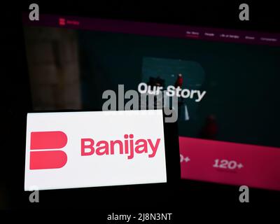 Personne tenant un smartphone avec le logo de la société française de divertissement Banijay Group sur écran devant le site. Mise au point sur l'affichage du téléphone. Banque D'Images