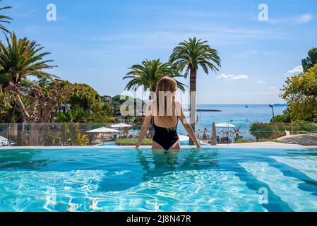 Vue arrière d'une femme qui profite de la piscine au spa de l'hôtel pendant les vacances d'été Banque D'Images