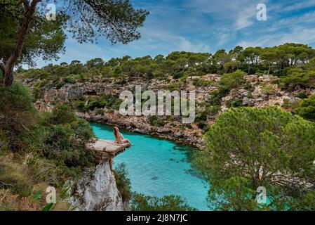 Vue à grand angle de la femme se détendant sur un pont brisé par une falaise rocheuse au-dessus de la mer Banque D'Images