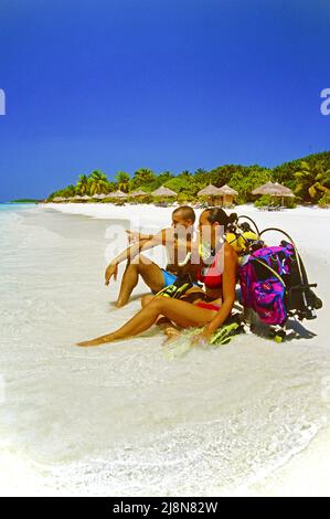 Couple avec équipement de plongée assis sur la plage de l'île maldivienne Reethi Beach, Baa-atoll, Maldives, océan Indien, Asie Banque D'Images