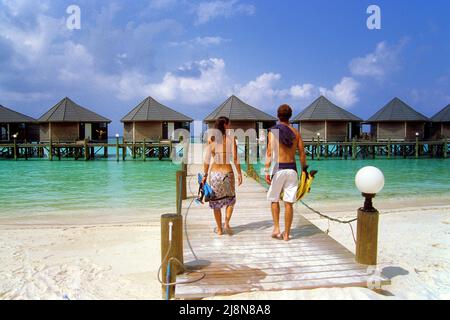 Couple sur la jetée dans les bungalows d'eau de luxe, Kuredu, l'atoll de Laviyani, l'océan Indien, l'Asie Banque D'Images