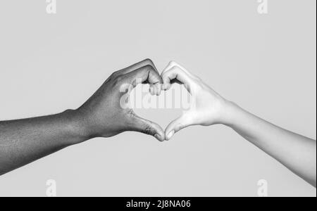 Les gens de différentes couleurs de peau mettent leurs mains ensemble faisant la forme de coeur dans le fond blanc. Noir et blanc Banque D'Images