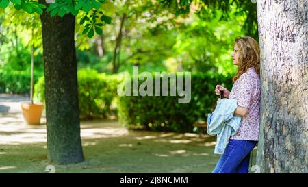 Femme séchée sur le tronc d'un immense arbre à la lumière du soleil de printemps chaud. Banque D'Images