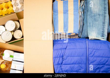 Vue de dessus des boîtes à dons avec vêtements et nourriture. Les bénévoles recueillent des dons. Don, charité, banque alimentaire, aide aux familles pauvres, migrants Banque D'Images