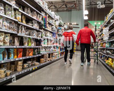 Kirkland, WA USA - vers février 2022: Vue d'un couple doux en costume rouge assorti, se tenant les uns les autres pendant qu'ils parcourent un marché alimentaire entier. Banque D'Images