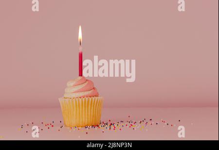 Petit gâteau avec une bougie allumée sur fond rose Banque D'Images