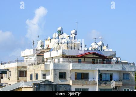 Paysage urbain chypriote traditionnel avec maisons blanches, plats satellites et réservoirs d'eau sur les toits, fond bleu ciel Banque D'Images