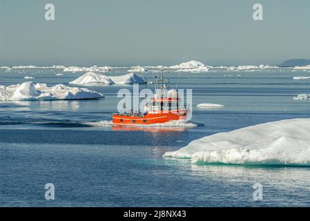 Petit bateau de pêche parmi les icebergs dans la baie de Disko, Groenland, Danemark Banque D'Images