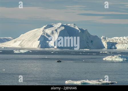 Petit bateau de pêche parmi les icebergs dans la baie de Disko, Groenland, Danemark Banque D'Images