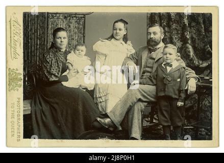 Portrait original de studio de carte de cabinet victorien du groupe familial victorien prospère moyen ou supérieur attrayant, mère et père, fille, fils et bébé. Il est intéressant de voir que la femme et les filles détournent leurs yeux et que l'homme et le garçon regardent la caméra avec confiance. Du studio d'A.G. Taylor, studios à Sunderland & South Shields, dans le nord de l'Angleterre, au Royaume-Uni vers 1895 Banque D'Images