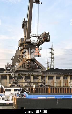 Mannheim, Allemagne - avril 2022 : grue déchargeant du charbon d'une barge industrielle dans une centrale électrique sur le Rhin. L'usine est exploitée par CKM. Banque D'Images