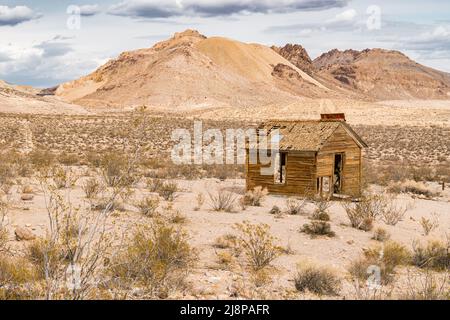 Ancienne maison abandonnée au milieu du désert du Nevada avec des montagnes en arrière-plan Banque D'Images