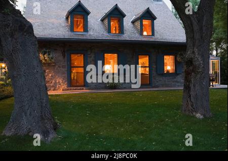 Vieux vers 1740 Maison en pierre de campagne de style Canadiana avec toit de bardeaux en bois de cèdre au crépuscule. Banque D'Images