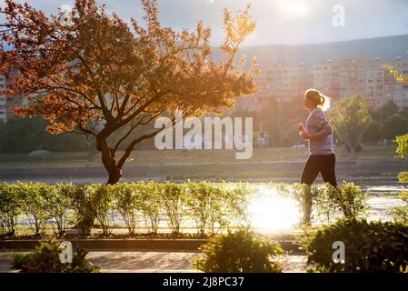 Femme qui fait du jogging dans un parc au bord de la rivière Banque D'Images