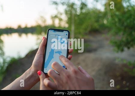 Un couple de touristes sur un voyage de camping, à la recherche du chemin par GPS sur un smartphone. Application avec une carte de la zone d'un smartphone. Banque D'Images