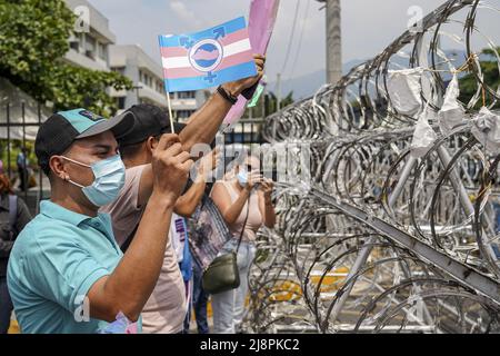 San Salvador, El Salvador. 17th mai 2022. Un démonstrateur porte un drapeau de fierté transgenre à côté d'une clôture barbelée lors d'une manifestation pour les droits des membres de la communauté LGBT, y compris une loi d'identité pour les personnes transgenres. La Journée internationale contre l'homophobie, la biphobie et la transphobie est commémorée chaque 17 mai afin de sensibiliser la population aux violations des droits LGBT, y compris les crimes haineux et les meurtres commis contre la communauté. Crédit : SOPA Images Limited/Alamy Live News Banque D'Images