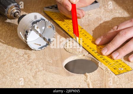 Travailleur avec fraise en action à l'atelier. Menuisier faisant des trous dans la planche de bois. BRICOLAGE Banque D'Images