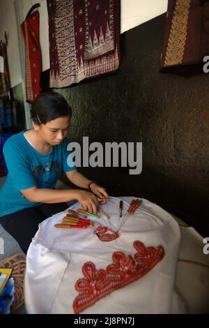 Une femme triant des motifs décoratifs sur le textile à l'aide d'un outil traditionnel à Sawahlunto, Sumatra Ouest, Indonésie. Banque D'Images