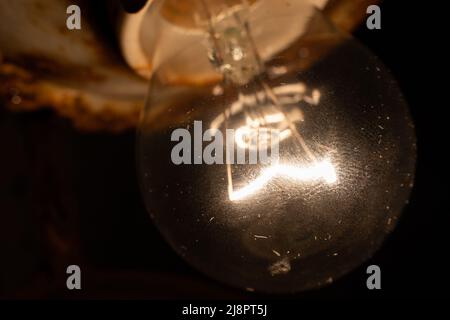 L'ancienne ampoule à incandescence s'allume dans l'obscurité pour un gros plan Banque D'Images