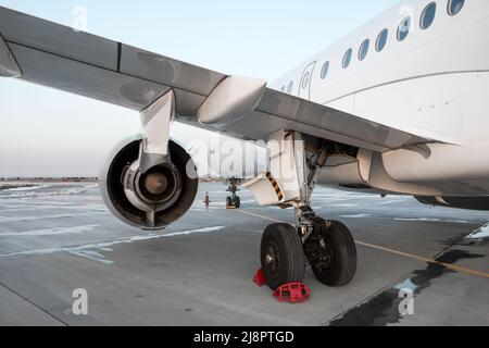 Avion passager blanc sur le tablier de l'aéroport. Gros plan de la partie arrière de l'aile et du train d'atterrissage principal Banque D'Images
