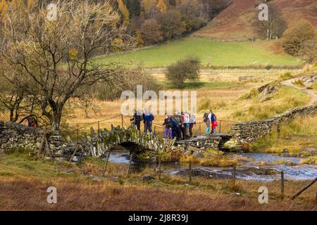 Marcheurs traversant le pont de Slater sur la rivière Brathay, Little Langdale, Lake District, Cumbria, Angleterre, ROYAUME-UNI Banque D'Images