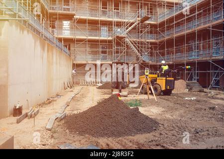 Un constructeur conduit un tombereau de chantier et une pelle hydraulique sur un nouveau chantier de construction. Équipement d'arpentage sur le chantier Banque D'Images