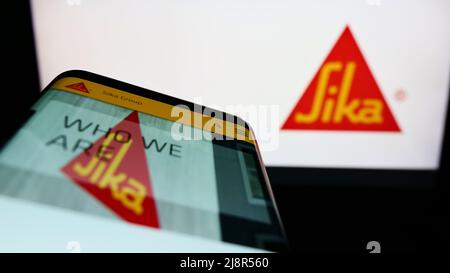 Smartphone avec le site Web de la société suisse de produits chimiques spécialisés Sika AG à l'écran devant le logo de l'entreprise. Faites la mise au point dans le coin supérieur gauche de l'écran du téléphone. Banque D'Images