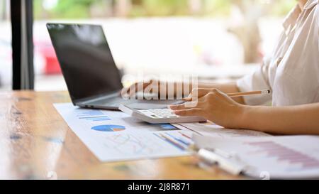 Vue arrière, gros plan, femme d'affaires ou comptable travaillant sur un rapport financier à son bureau. Banque D'Images