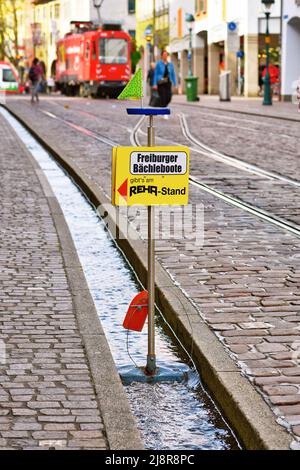 Freiburg, Allemagne - avril 2022: Panneau indiquant la boutique qui vend de petits bateaux en bois jouets les enfants peuvent flotter sur le ruisseau appelé 'Bächle' dans le centre-ville Banque D'Images