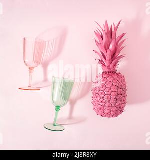 Plage d'été concept de verres à vin et frais, tropical pastel rose ananas fruits. Ambiance de vacances. Pose à plat. Banque D'Images