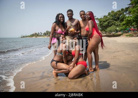 Groupe de jeunes hommes et femmes africains à la plage posant et s'amusant. Ensemble. Banque D'Images