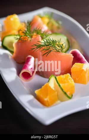 Buffet de tranches de saumon marinées avec radis, concombre et cubes d'orange Banque D'Images