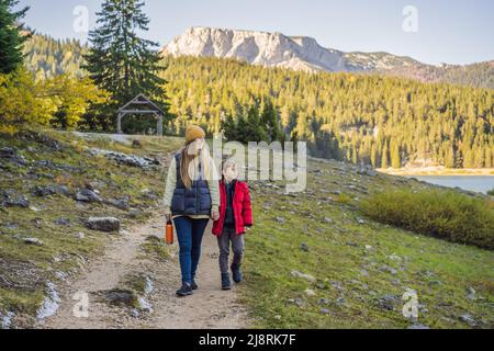 Les touristes de maman et de fils en arrière-plan de la vue panoramique du matin sur le lac Noir Crno Jezero. Scène estivale calme du parc de Durmitor Nacionalni, Zabljak Banque D'Images
