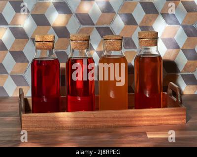 Quatre bouteilles de thé froid aux fruits, rooibos, vert et noir, dans un plateau en bois sur une table en bois Banque D'Images